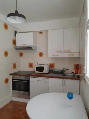a kitchen with white cabinets and a white table at grand T3 centre ville climatisé in Corte