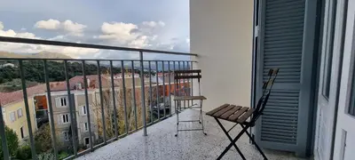 a balcony with a chair and a view of a building at grand T3 centre ville climatisé in Corte