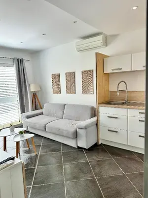 a living room with a couch and a kitchen at Hébergement avec piscine in Sotta