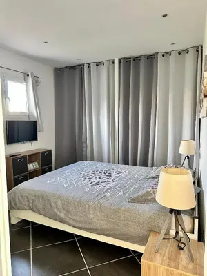 a bedroom with a bed and a window with curtains at Hébergement avec piscine in Sotta