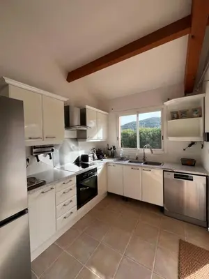 a kitchen with white cabinets and a large window at Casa Alivu in Pietrosella