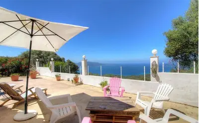 a patio with chairs and a table with an umbrella at Location familiale 6 personnes entre Propriano et Olmeto in Olmeto