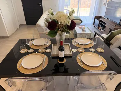 a black table with plates and a vase of flowers at Villa mitoyenne - Luxury house between sea and nature in Ghisonaccia