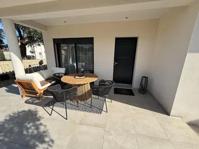 a patio with a table and chairs and a couch at Villa mitoyenne - Luxury house between sea and nature in Ghisonaccia