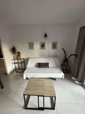 a white bedroom with a bed and a table at Appartement pour 6 pers avec piscine in Zonza