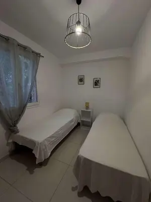 a bedroom with two beds and a chandelier at Appartement pour 6 pers avec piscine in Zonza