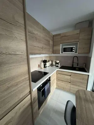 a small kitchen with wooden cabinets and a sink at Appartement pour 6 pers avec piscine in Zonza