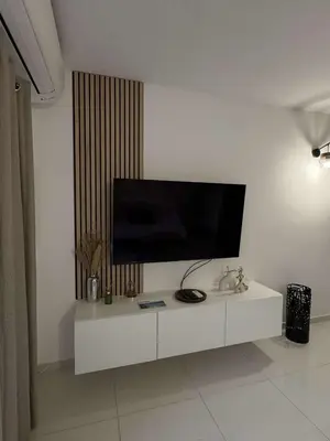a white entertainment center with a flat screen tv on a wall at Appartement pour 6 pers avec piscine in Zonza