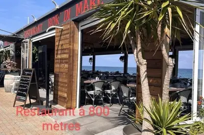 a restaurant with tables and chairs in front of the ocean at Appartement bord de mer in San-Nicolao