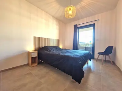 a bedroom with a bed and a chair and a window at Résidence Poggiarelli in Sainte-Lucie de Porto-Vecchio