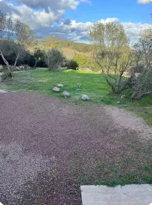 a gravel driveway with a field of grass and trees at Charmant T2 in Sotta