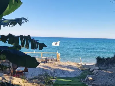 a beach with a white flag and the ocean at Bungalow cosy avec terrasse - 2 pers. - API-1-52-1974 in Linguizzetta