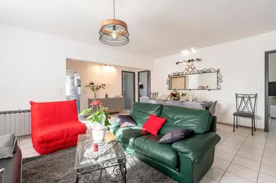 a living room with a green couch and a red chair at Le Ricci - Climatisé plages à 2 km in Ajaccio