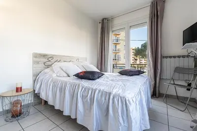 a bedroom with a bed with white sheets and a window at Le Ricci - Climatisé plages à 2 km in Ajaccio