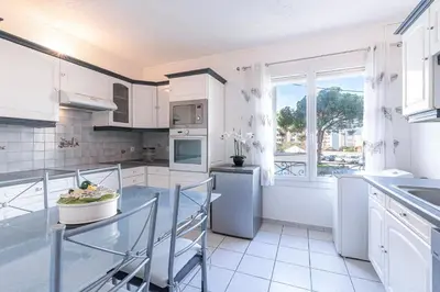 a kitchen with white cabinets and a table and a window at Le Ricci - Climatisé plages à 2 km in Ajaccio