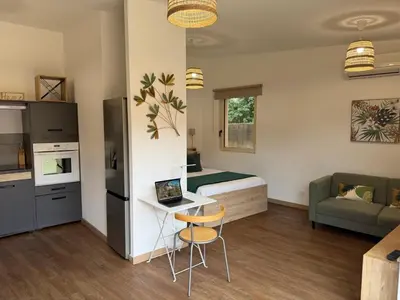 a small room with a bed and a table with a laptop at Grand Studio hyper centre PORTO-VECCHIO in Porto-Vecchio
