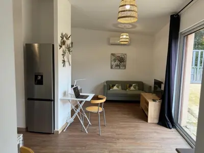 a kitchen with a refrigerator and a table and a couch at Grand Studio hyper centre PORTO-VECCHIO in Porto-Vecchio