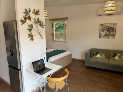 a small room with a bed and a laptop on a table at Grand Studio hyper centre PORTO-VECCHIO in Porto-Vecchio