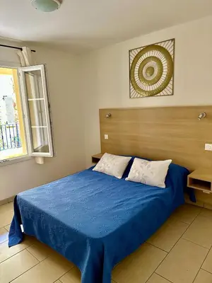 a bedroom with a blue bed with a wooden headboard at Logement PMR 2-4 personnes - piscine - clim - 100m de la plage in Sari Solenzara