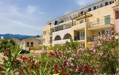 a building with flowers in front of it at Logement PMR 2-4 personnes - piscine - clim - 100m de la plage in Sari Solenzara