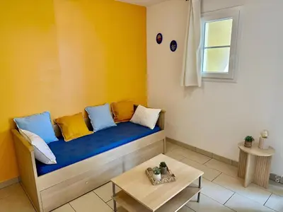 a room with a couch with colorful pillows on it at Logement PMR 2-4 personnes - piscine - clim - 100m de la plage in Sari Solenzara