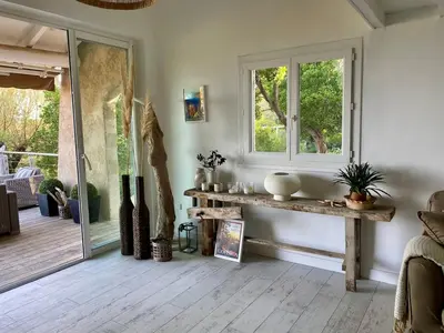 a living room with a table and a window at Villa bord de plage à pied proche Pinarello in Sainte-Lucie de Porto-Vecchio
