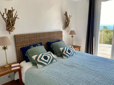 a bedroom with a blue bed with pillows and a window at Villa bord de plage à pied proche Pinarello in Sainte-Lucie de Porto-Vecchio