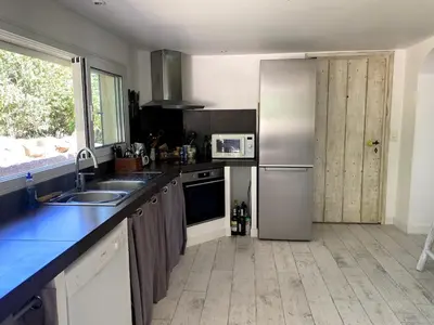 a kitchen with a stainless steel refrigerator and a sink at Villa bord de plage à pied proche Pinarello in Sainte-Lucie de Porto-Vecchio