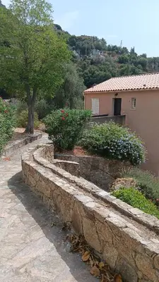 a stone retaining wall with flowers and a house at Maison pour 6 avec piscine in Lama