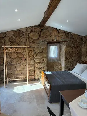 a bedroom with a stone wall with a bed in it at Bergerie du Riccio avec piscine privée in Cauro