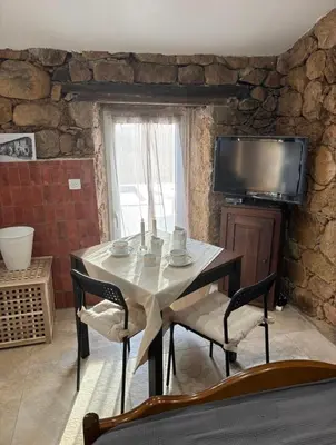 a stone house with two chairs and a table at Bergerie du Riccio avec piscine privée in Cauro