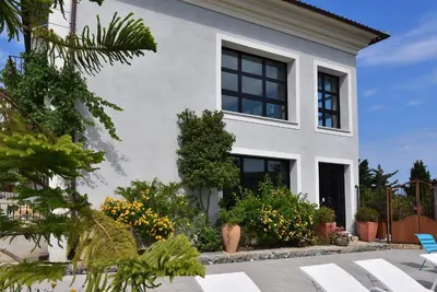 a white house with black windows and plants at Appart'hotel Fior Di Ribba in Sartène