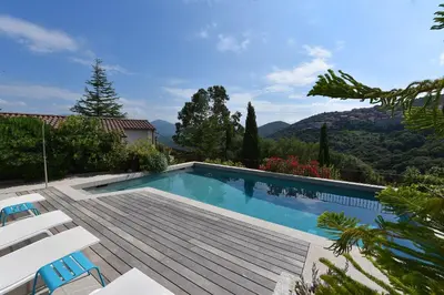 a swimming pool with a deck and two chairs at Appart'hotel Fior Di Ribba in Sartène
