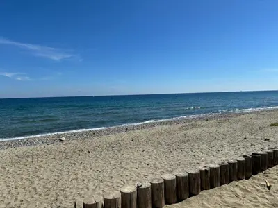 a beach with a fence on the sand and the ocean at Vacances idéales in San-Nicolao