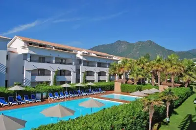 a hotel with a swimming pool with chairs and umbrellas at Vacances idéales in San-Nicolao