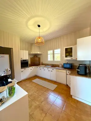 a large kitchen with white cabinets and a chandelier at Maison 4 chambres vue mer Jardin et plage à 1 min in Olmeto
