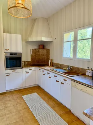 a large kitchen with white cabinets and a chandelier at Maison 4 chambres vue mer Jardin et plage à 1 min in Olmeto