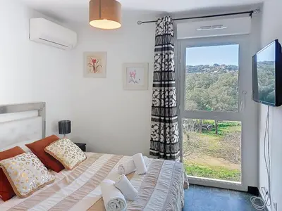 a bedroom with a bed and a large window at Apartment La Boétie by Interhome in Porto-Vecchio