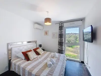 a bedroom with a bed with a tv and a window at Apartment La Boétie by Interhome in Porto-Vecchio