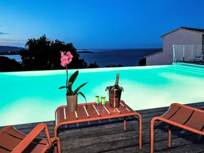 a table with a bottle of wine and two chairs by a swimming pool at Holiday Home Anna Maria by Interhome in Porto-Vecchio