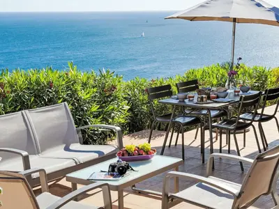 a patio with a table and chairs and the ocean at Holiday Home Babo by Interhome in Porto-Vecchio