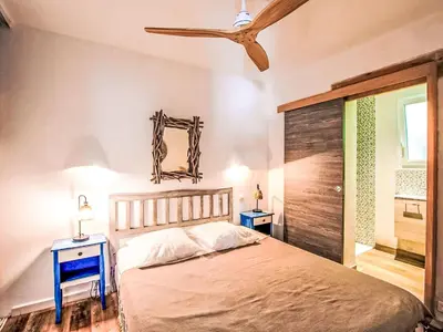a bedroom with a bed with two night stands and two tables at Holiday Home Haut Casa Blue by Interhome in Sainte-Lucie de Porto-Vecchio