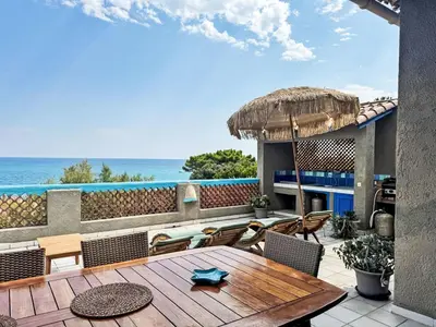 a patio with a table and chairs and the ocean at Holiday Home Haut Casa Blue by Interhome in Sainte-Lucie de Porto-Vecchio