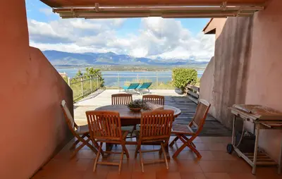 a table and chairs on a balcony with a view of the water at Villa Piscine Vue Mer in Porto-Vecchio