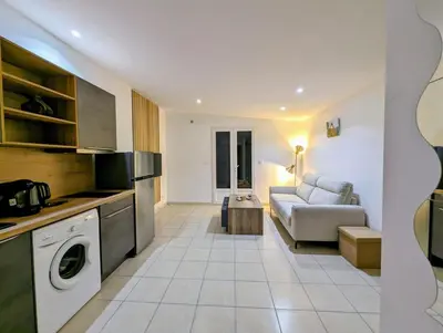 a kitchen and living room with a couch and a table at charmante maisonnette avec spa privatif in Zonza