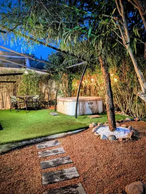 a garden with a tree and a stone walkway at charmante maisonnette avec spa privatif in Zonza