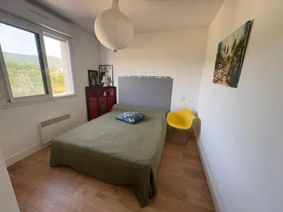 a bedroom with a bed and a yellow chair at Appartement lumineux à Ajaccio 2 chambres in Ajaccio