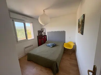 a small bedroom with a bed and a yellow chair at Appartement lumineux à Ajaccio 2 chambres in Ajaccio