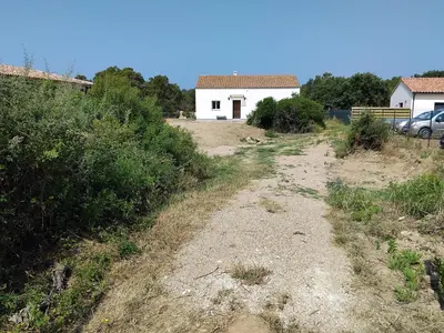 a dirt road with a white house in the background at villa au calme à Figari in Figari