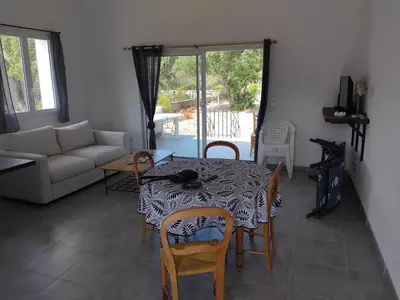 a living room with a table and chairs and a couch at villa au calme à Figari in Figari